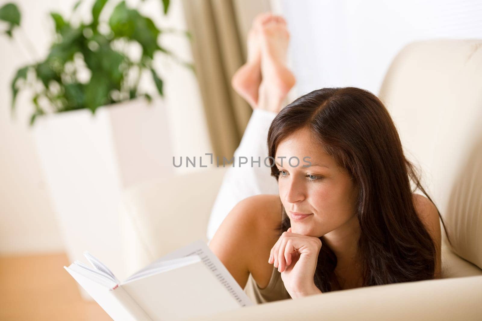 Young happy woman read book on sofa