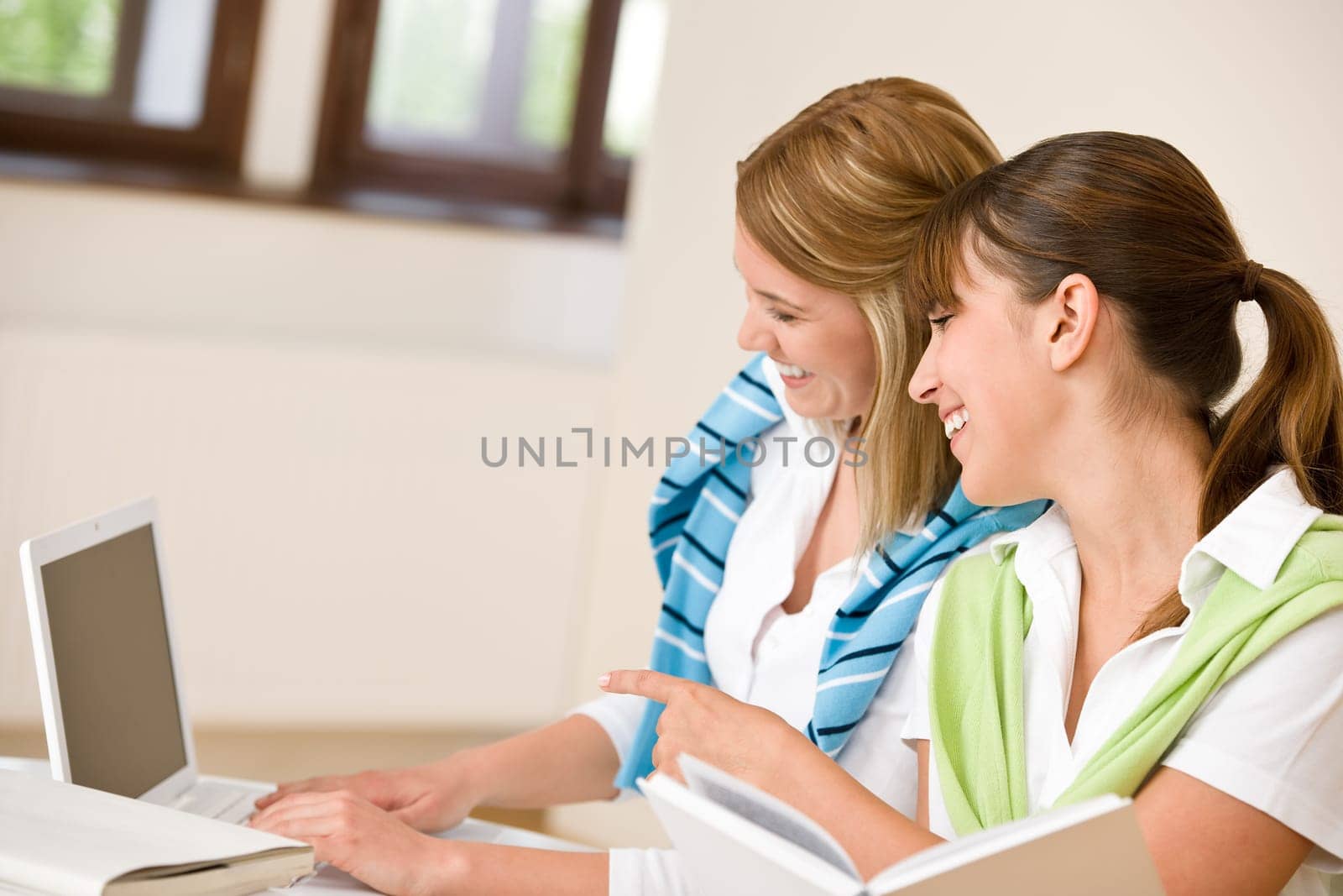 Student at home - two woman with book and laptop