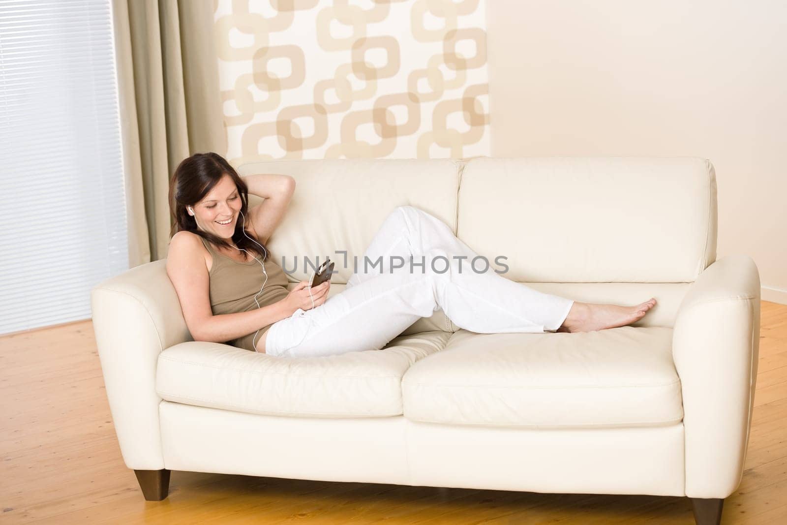 Woman holding music player listening on sofa home
