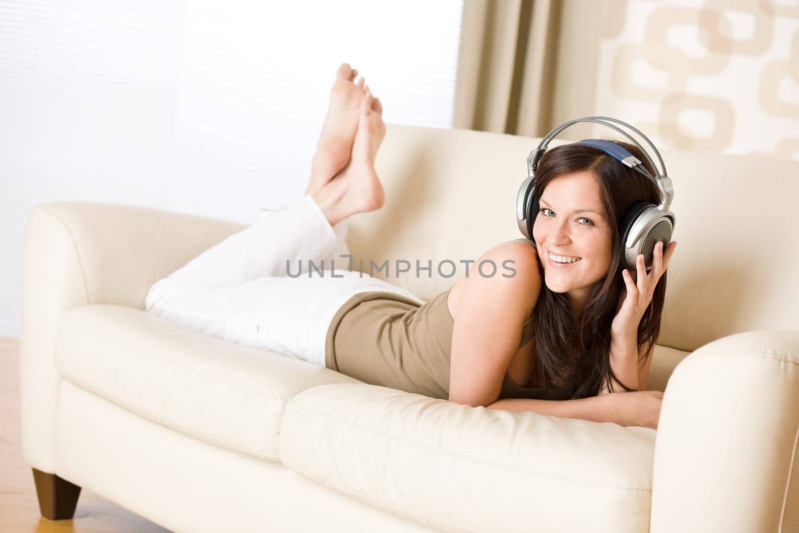Smiling woman with headphones  listen to music in lounge