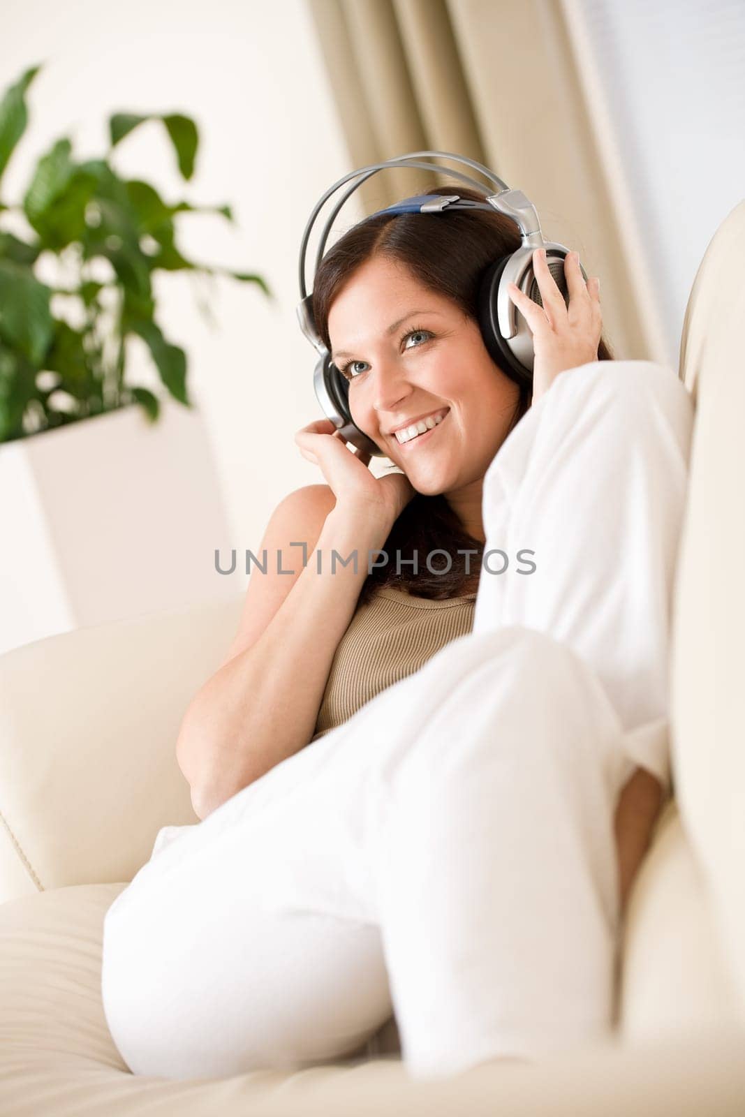 Smiling woman with headphones  listen to music in lounge