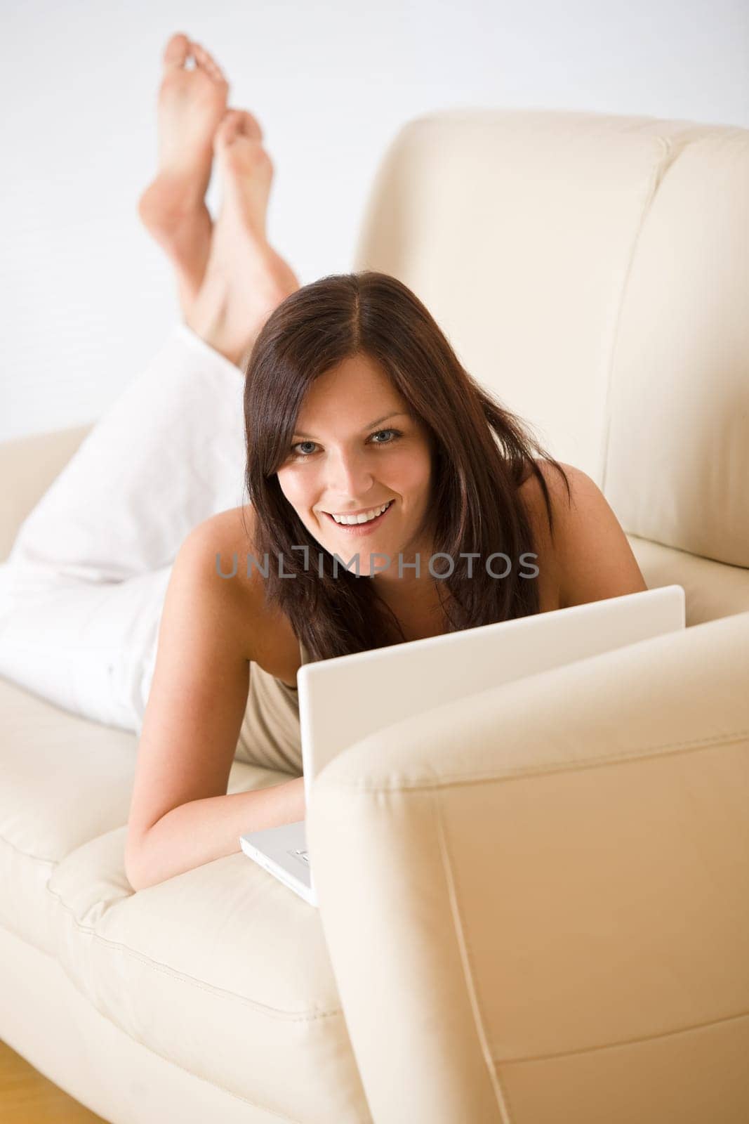 Young woman with laptop on sofa home in living room