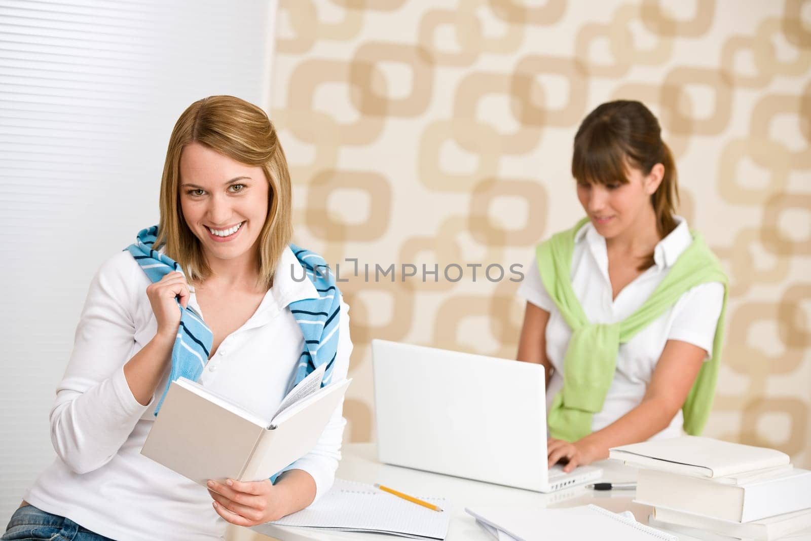 Student at home - two woman with book and laptop