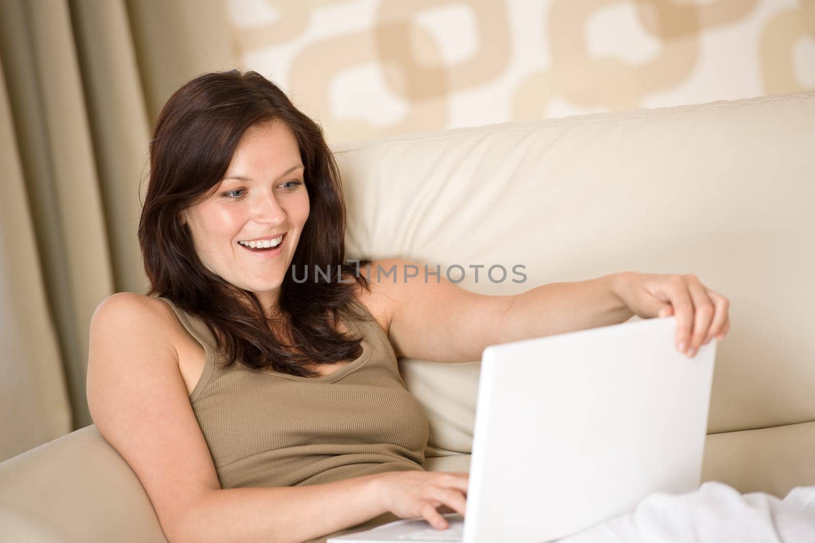 Smiling woman sitting with laptop sofa