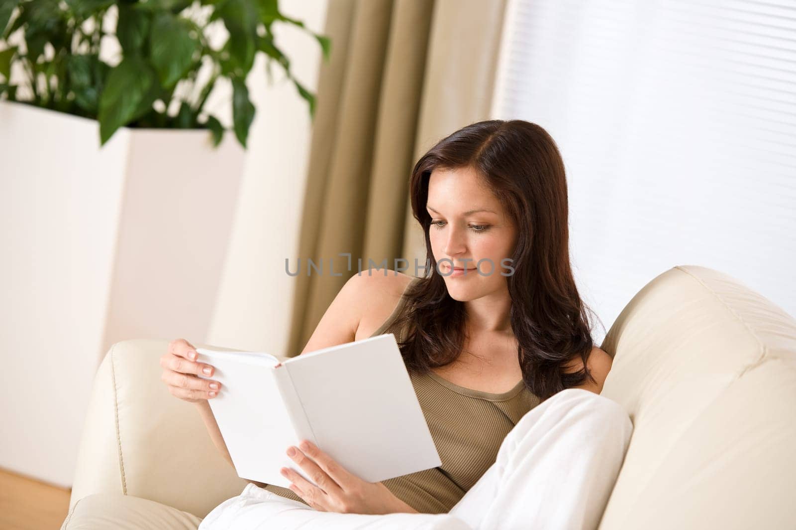 Young happy woman read book on sofa