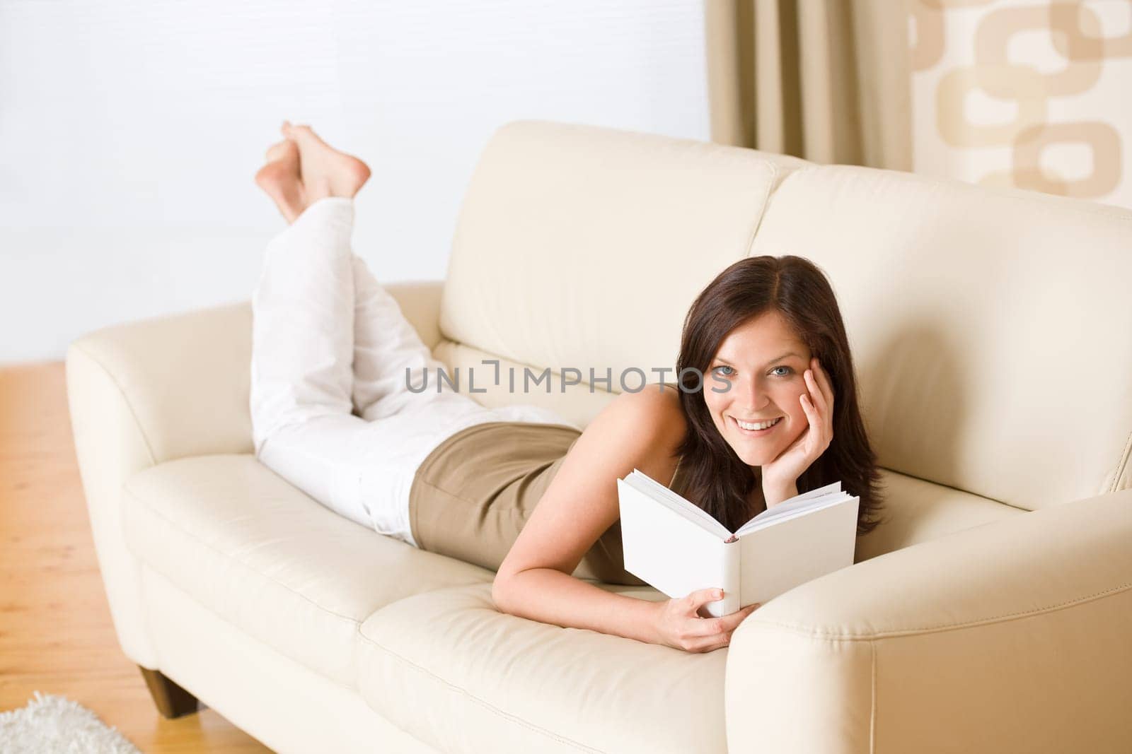 Young happy woman read book on sofa