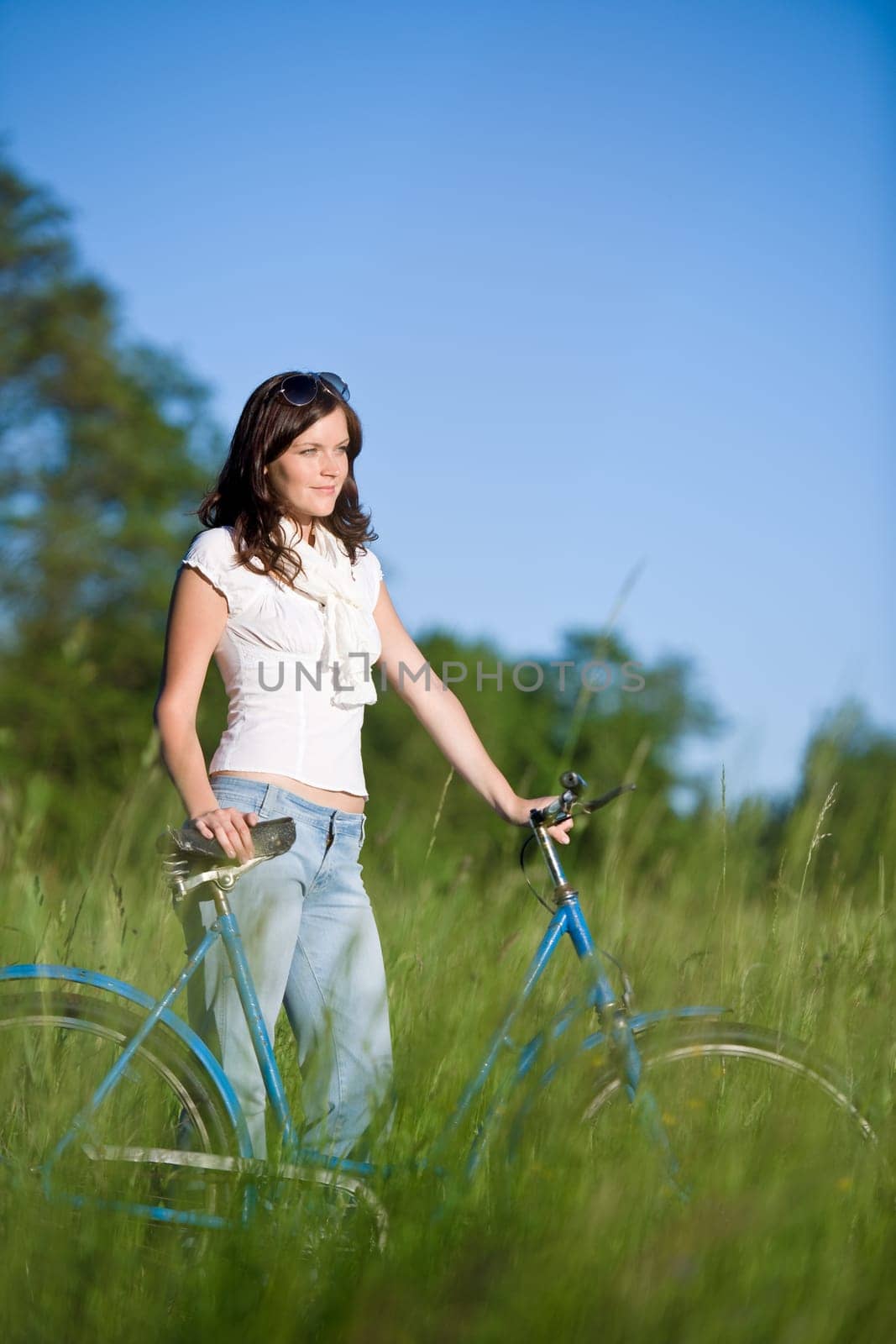 Woman with old-fashioned bike in meadow