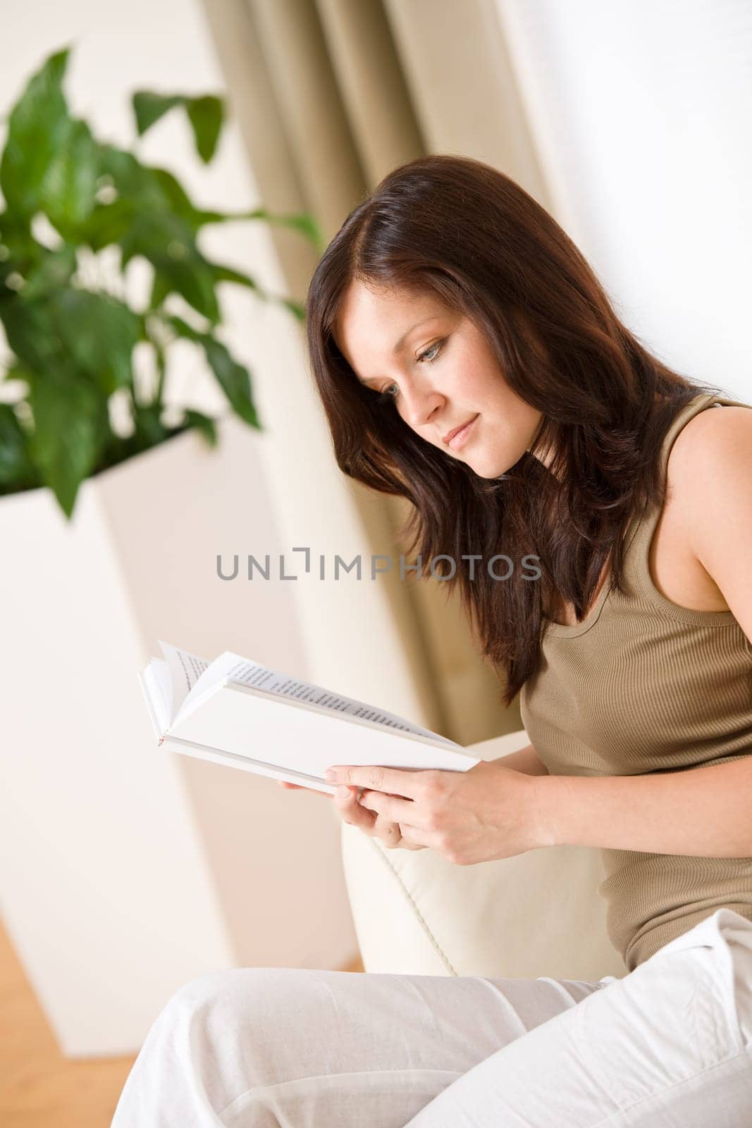 Young happy woman read book on sofa