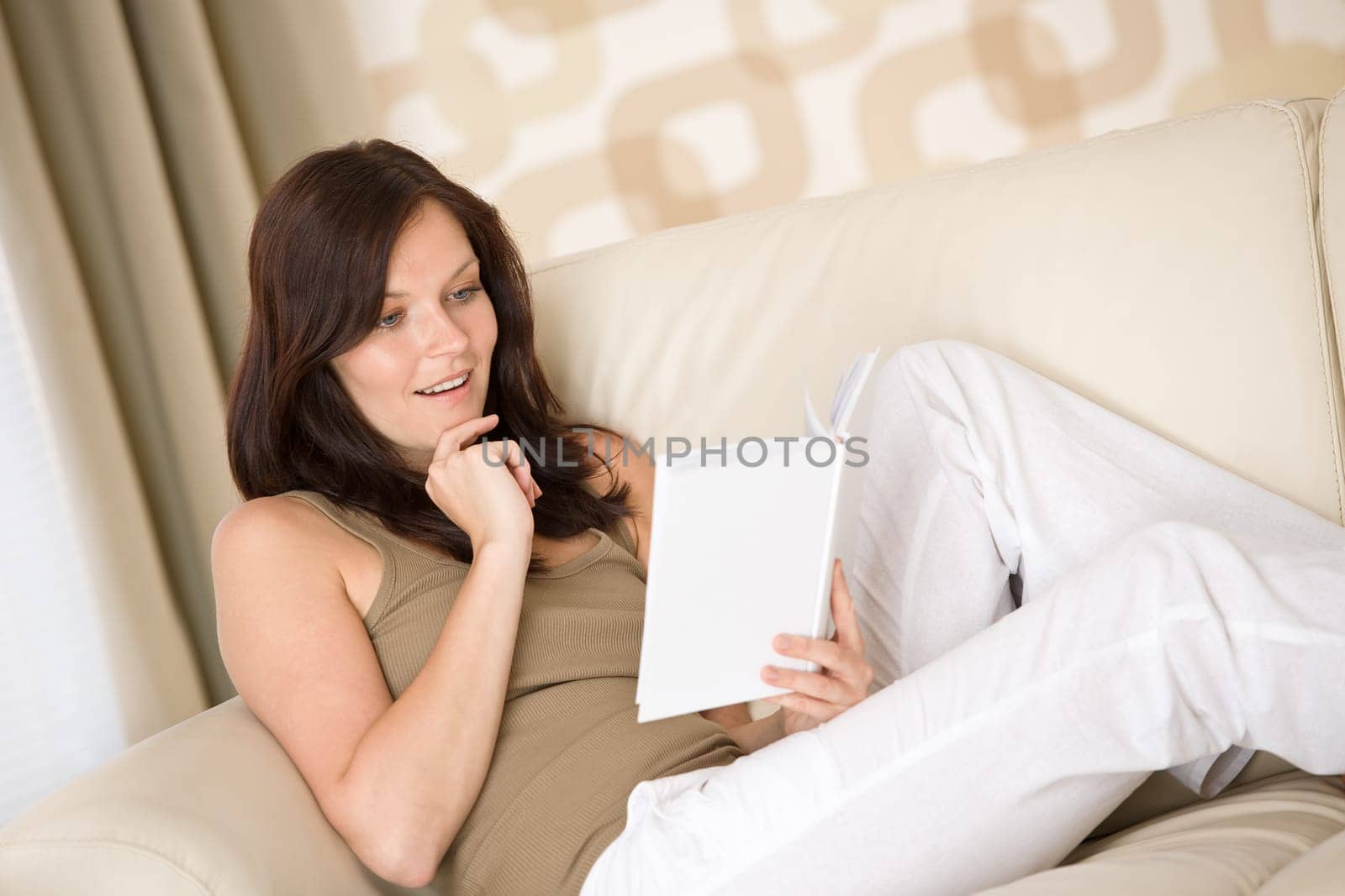 Young happy woman read book on sofa