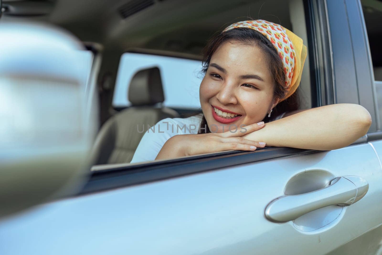 Smiling female driving vehicle on the road on a bright day. Sticking her head out the windshield by itchaznong