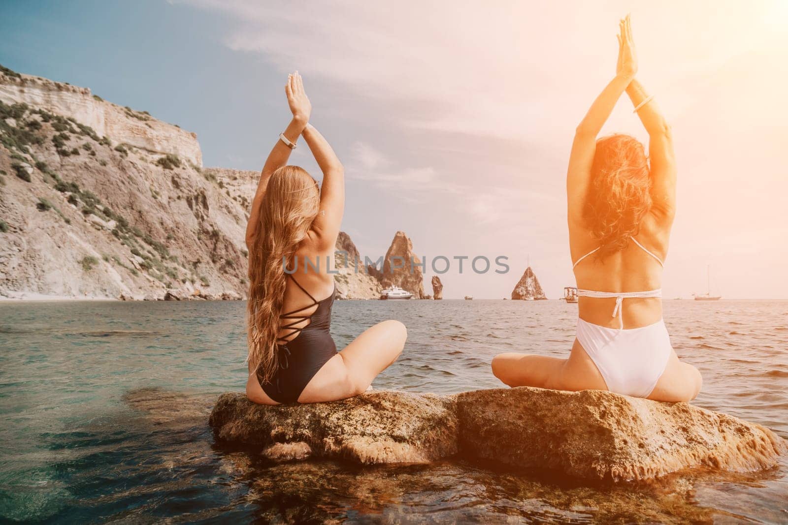 Woman sea yoga. Back view of free calm happy satisfied woman with long hair standing on top rock with yoga position against of sky by the sea. Healthy lifestyle outdoors in nature, fitness concept.