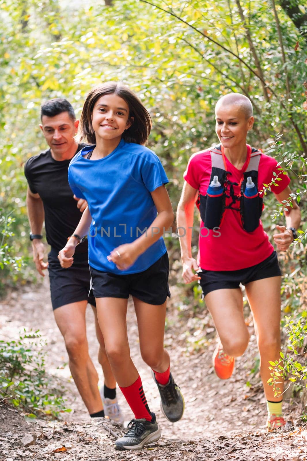 vertical photo of a happy family practicing trail running through the forest, concept of sport in nature and healthy family lifestyle