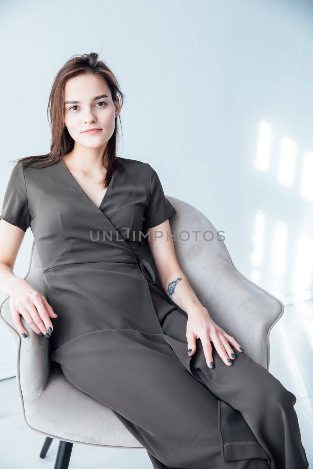 a woman in black dress sits in a chair in a bright room