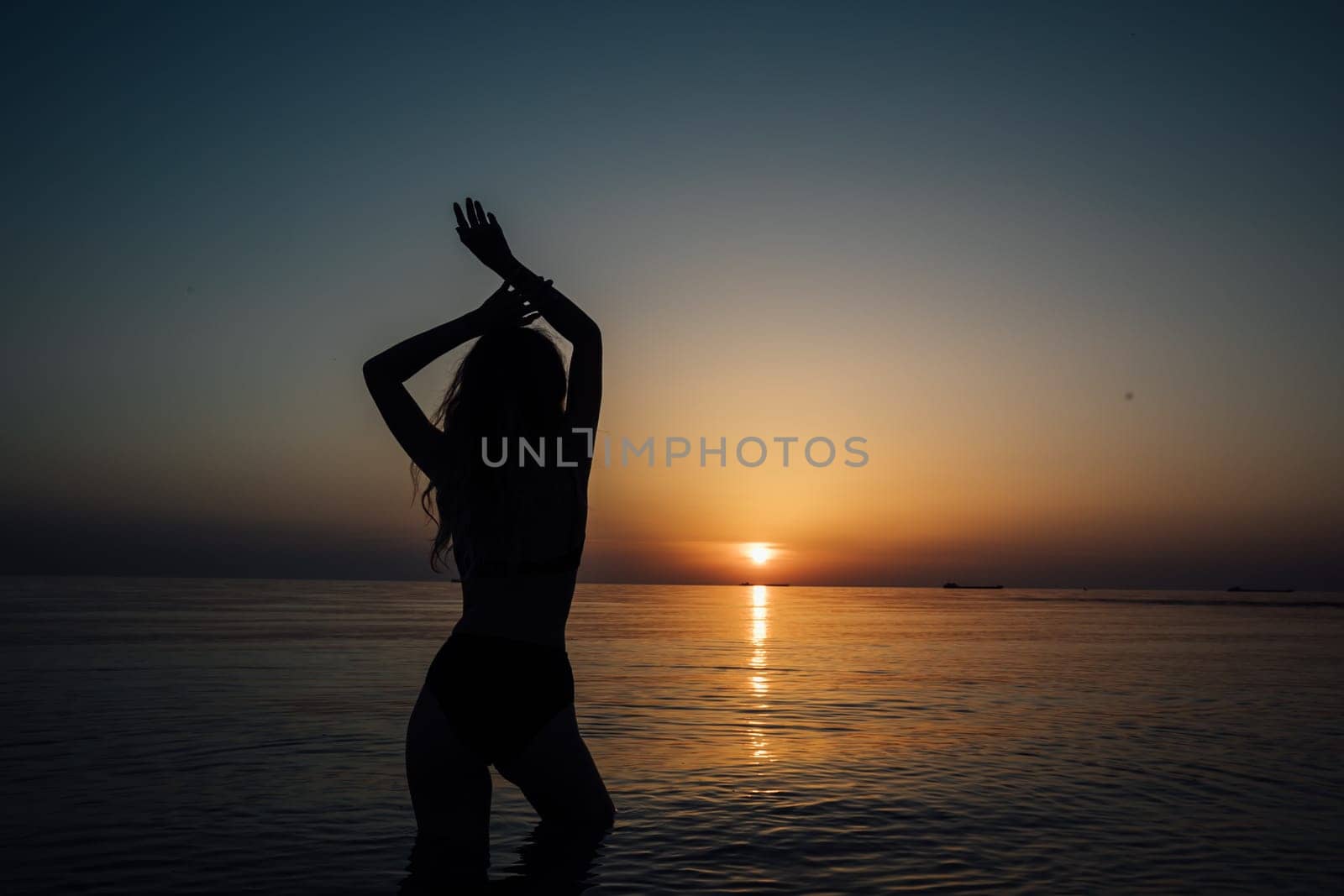 silhouette of woman in a swimsuit on the beach at sunset by the sea walk rest