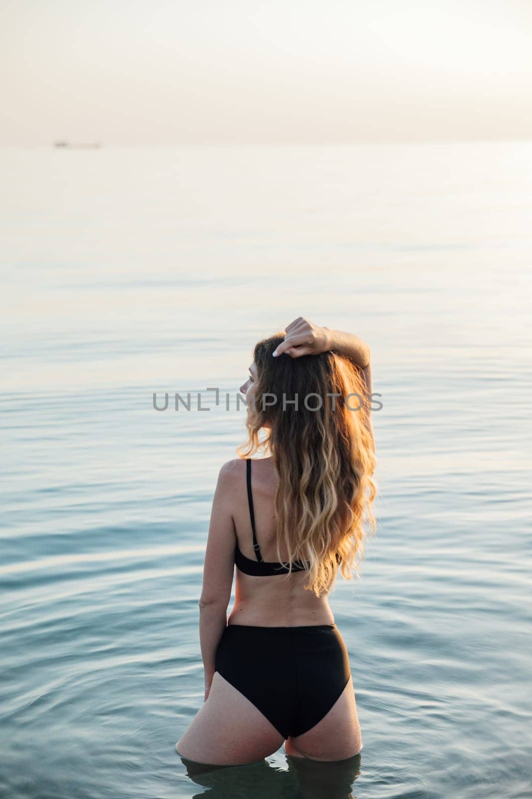 woman in a black swimsuit stands in the water in the sea rest on the beach