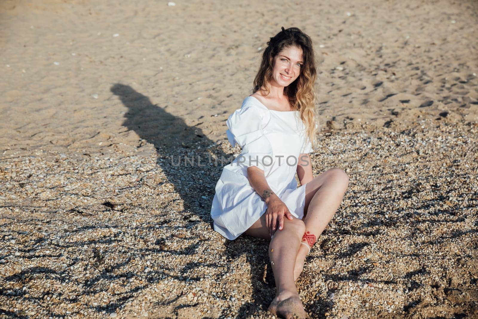 a woman sitting on small pebbles on the beach rest walk