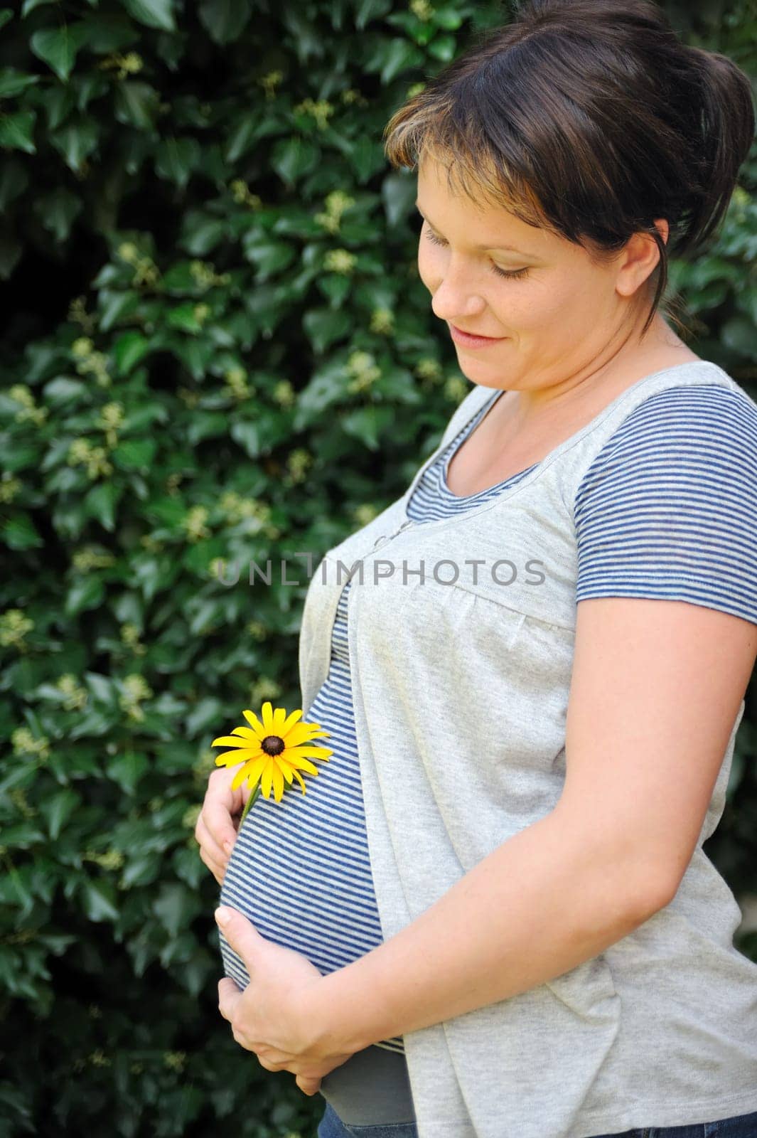Pregnant woman holding her belly and yellow flower