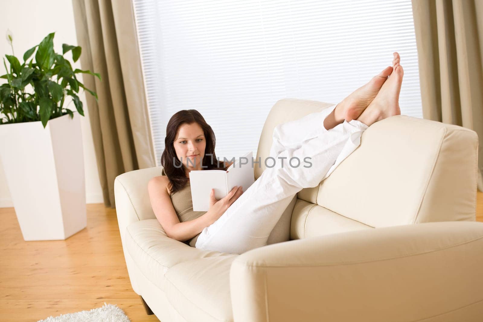 Young happy woman read book on sofa