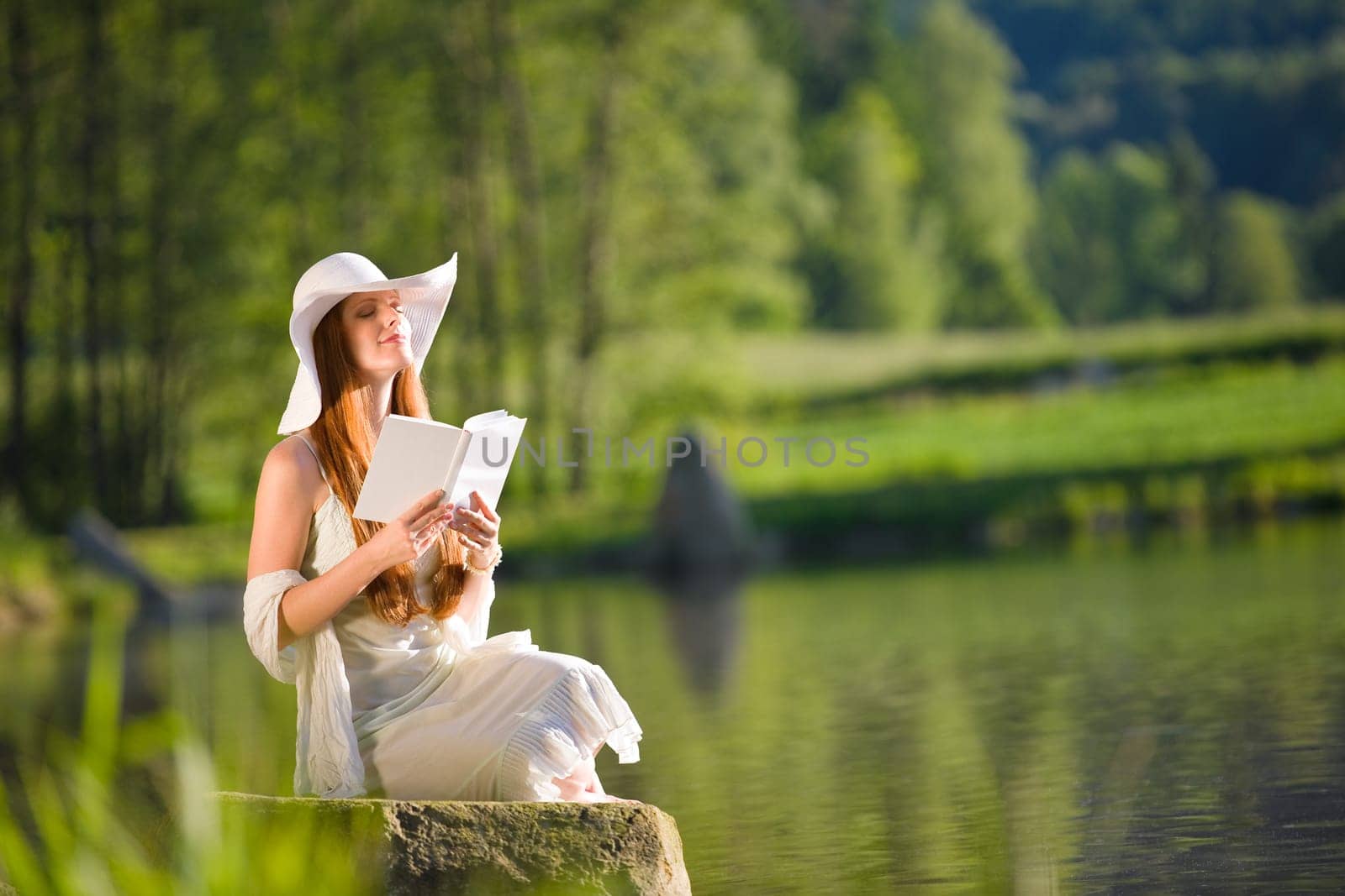 Long red hair romantic woman relax by lake with book