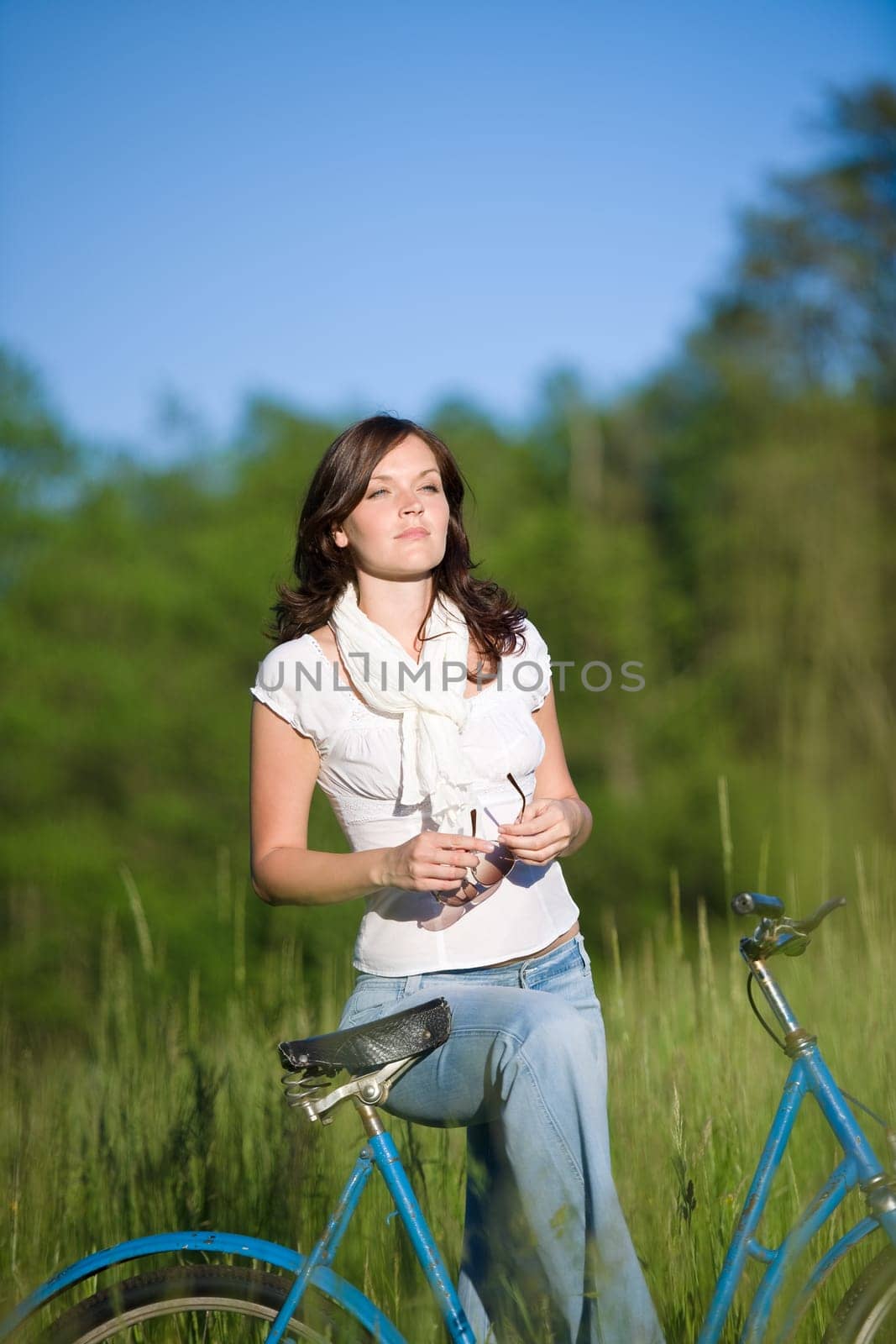 Woman with old-fashioned bike in meadow