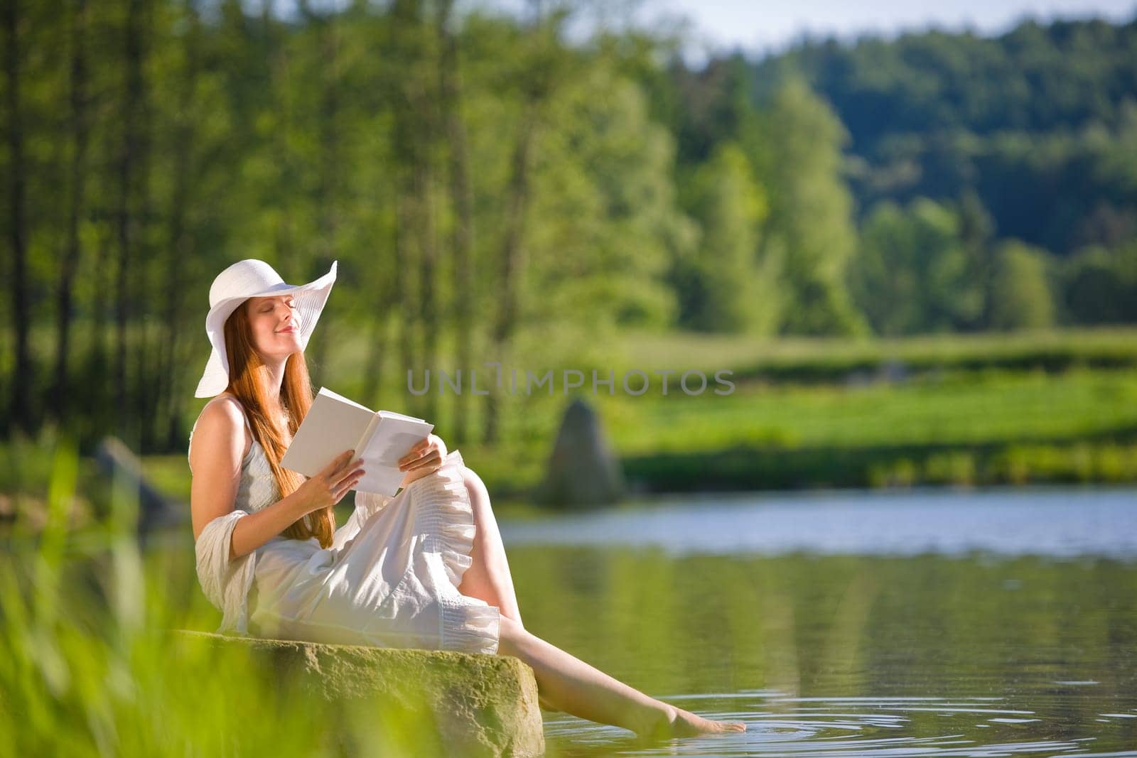 Long red hair romantic woman relax by lake with book