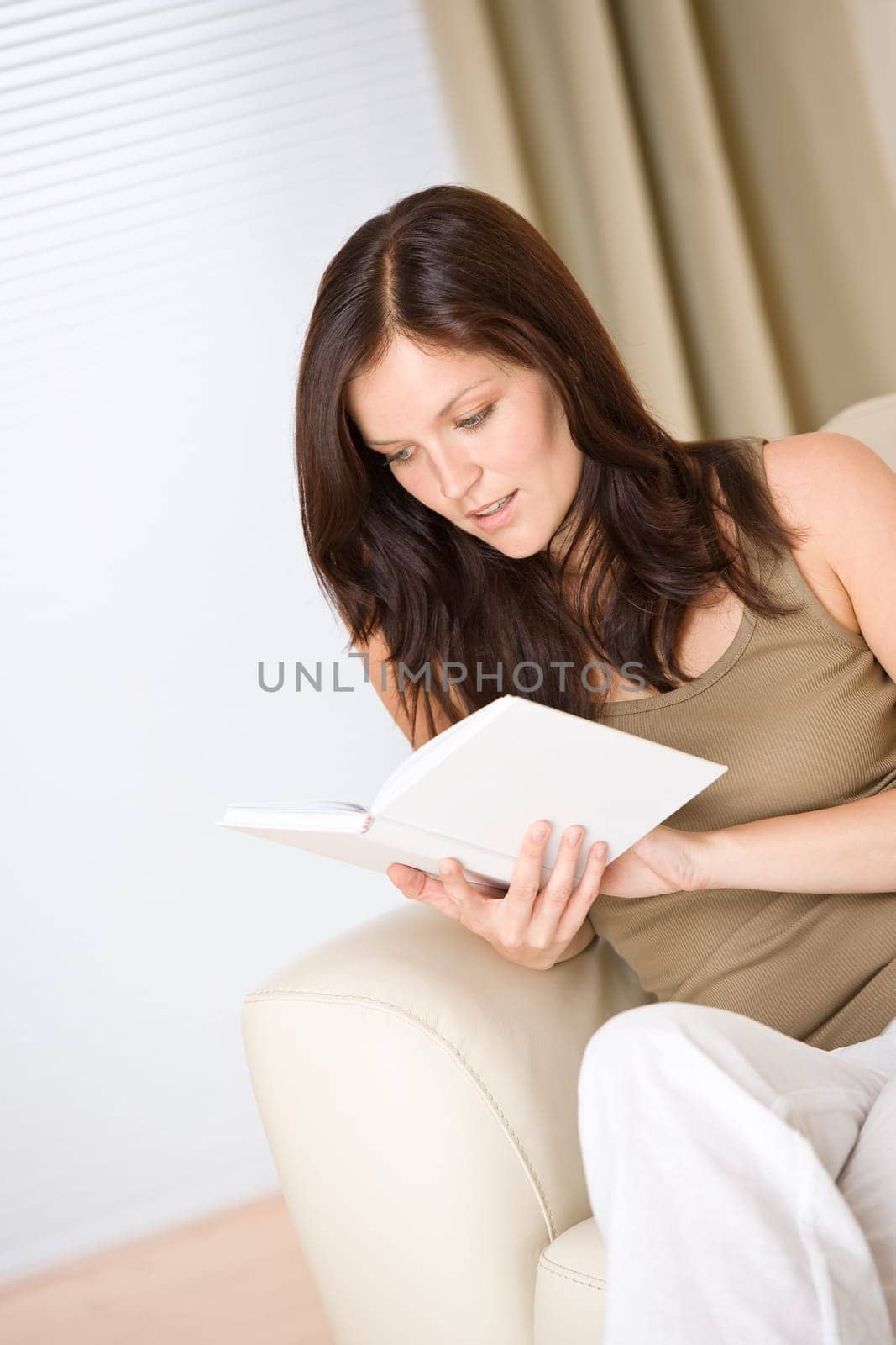 Young happy woman read book on sofa