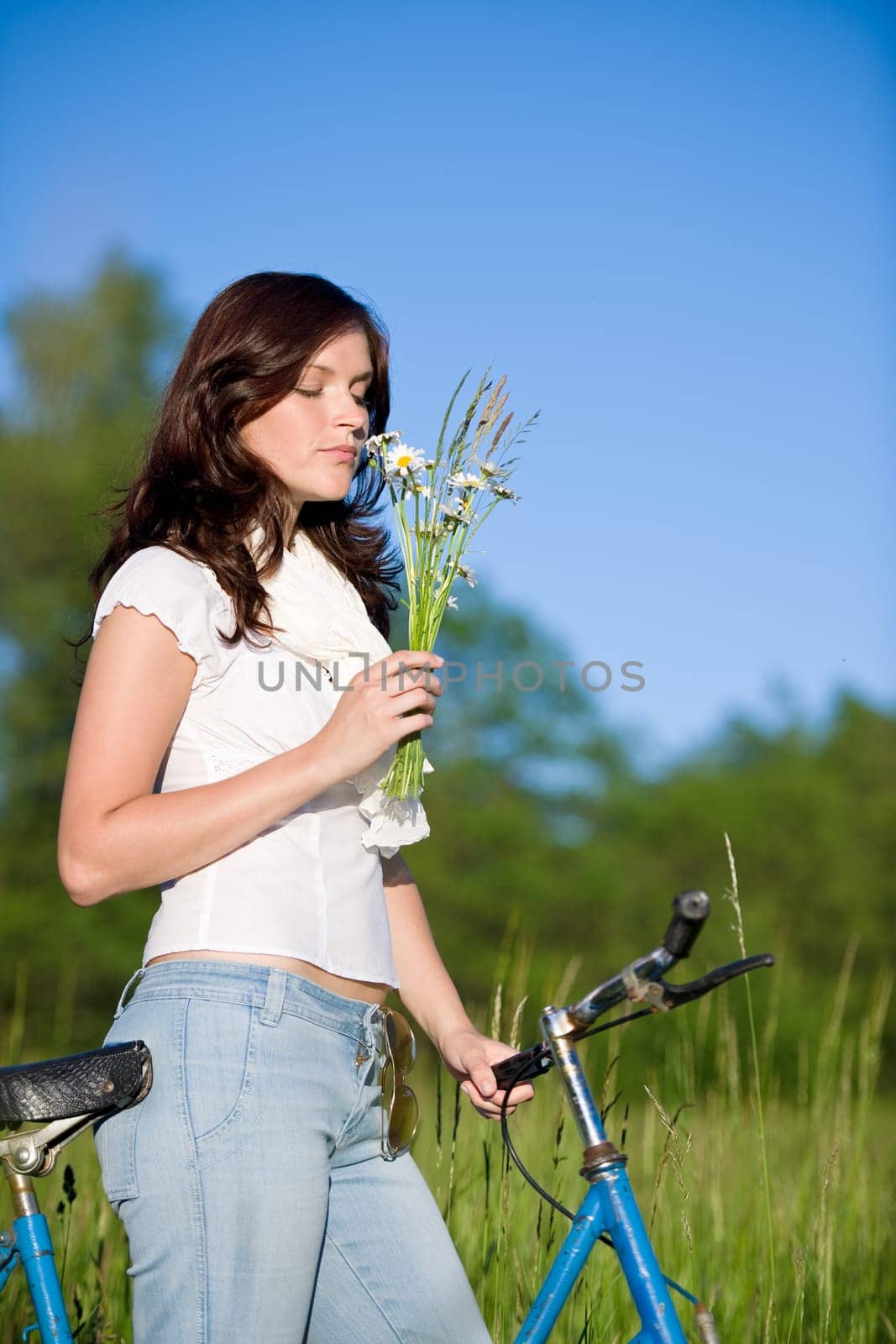 Woman with old-fashioned bike in meadow