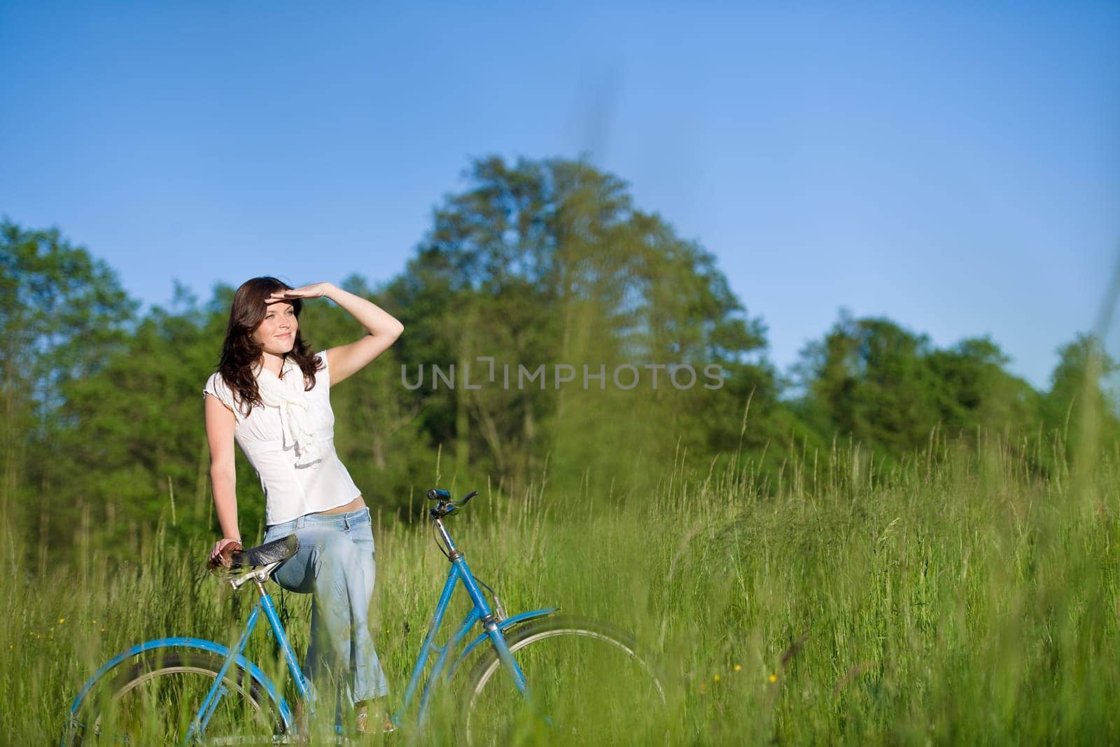 Woman with old-fashioned bike in meadow