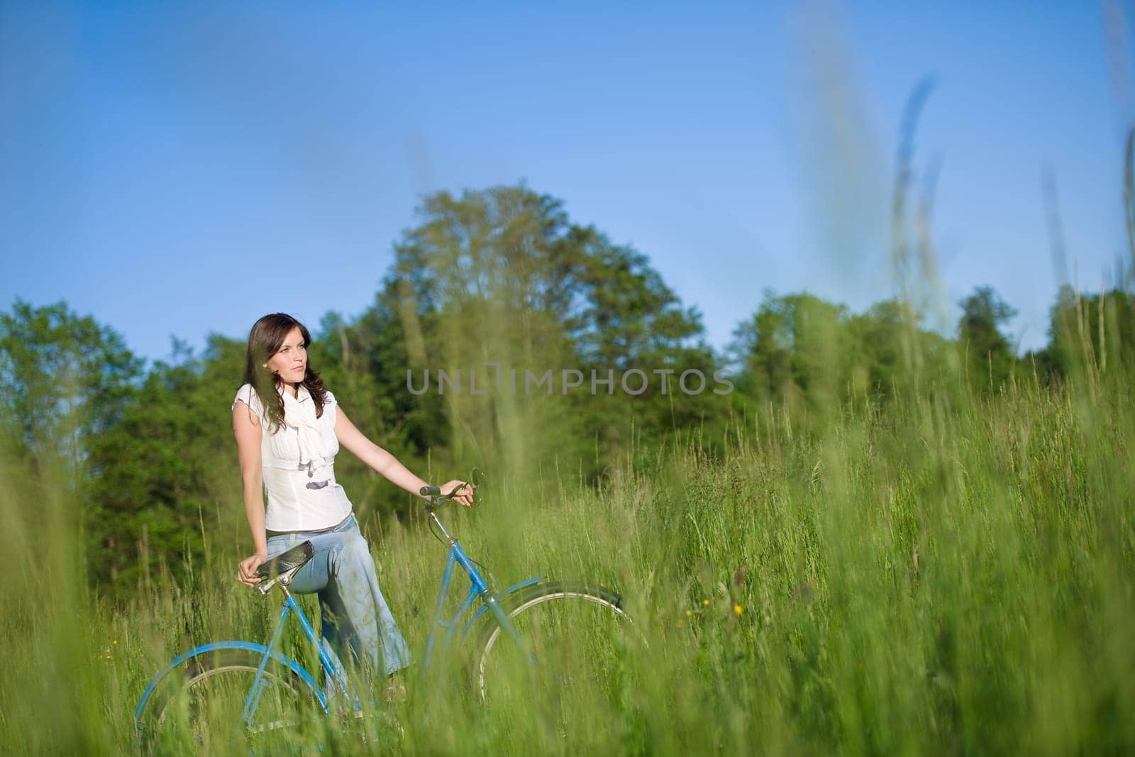 Woman with old-fashioned bike in meadow