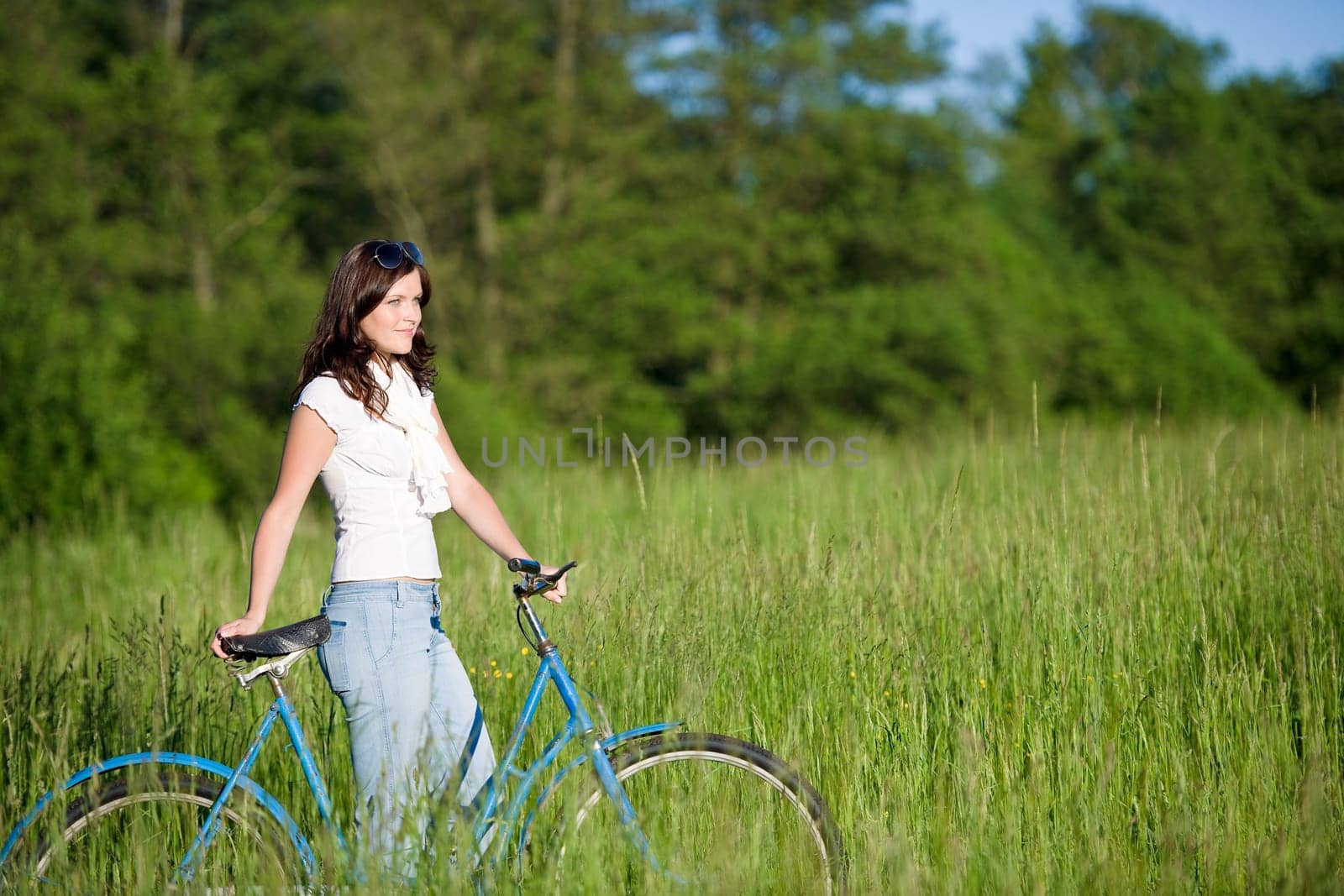 Woman with old-fashioned bike in meadow