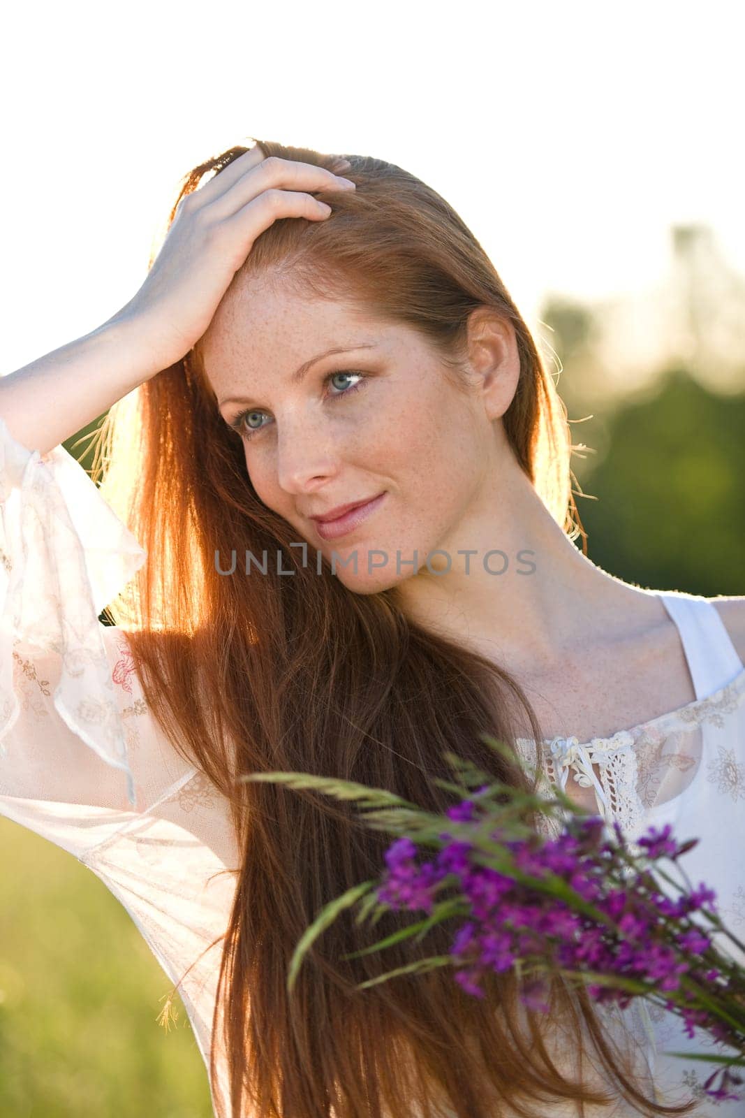 Long red hair woman in romantic sunset meadow