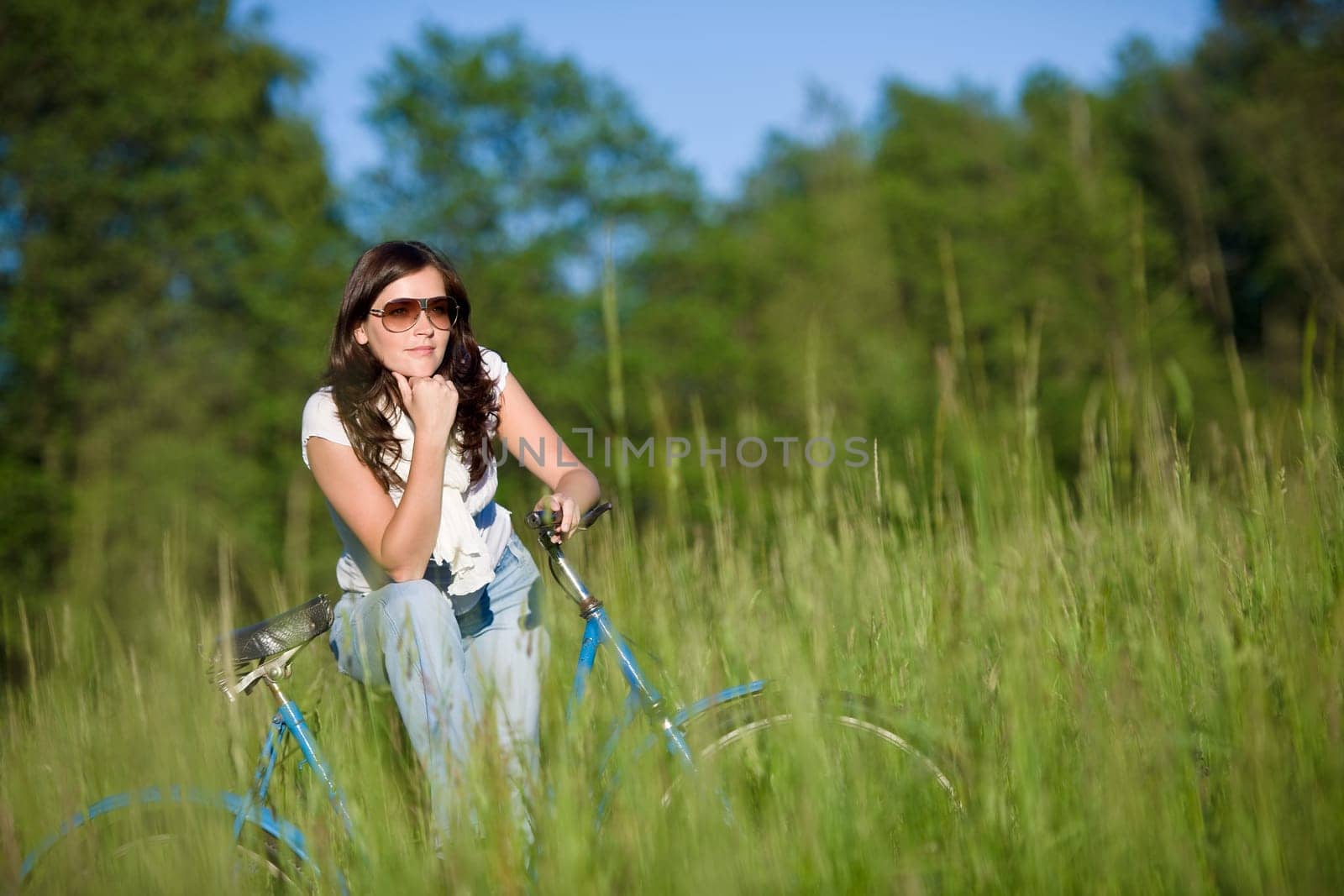 Woman with old-fashioned bike in meadow