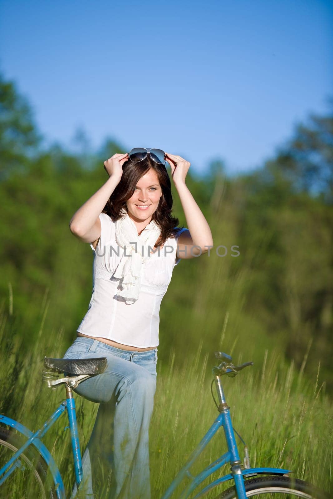 Woman with old-fashioned bike in meadow