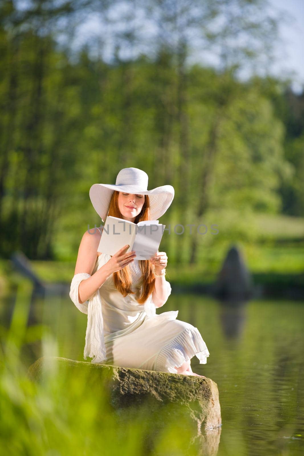 Long red hair romantic woman relax by lake with book