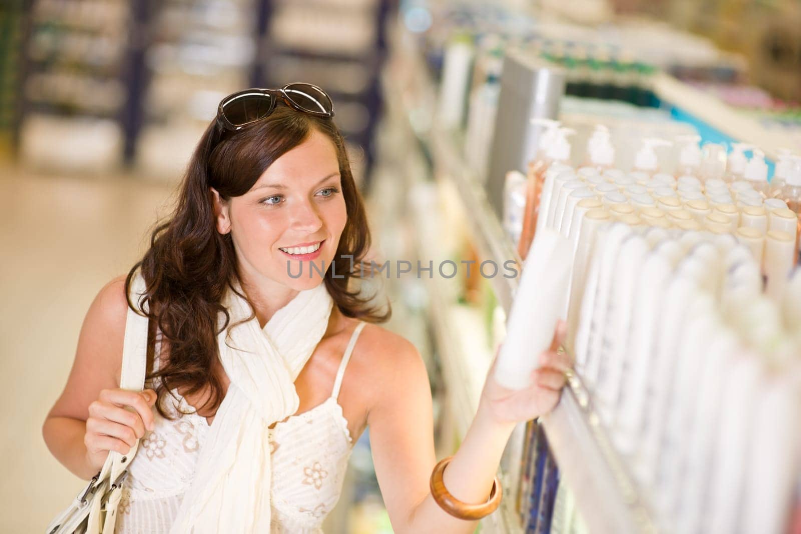 Shopping cosmetics - smiling woman choose shampoo