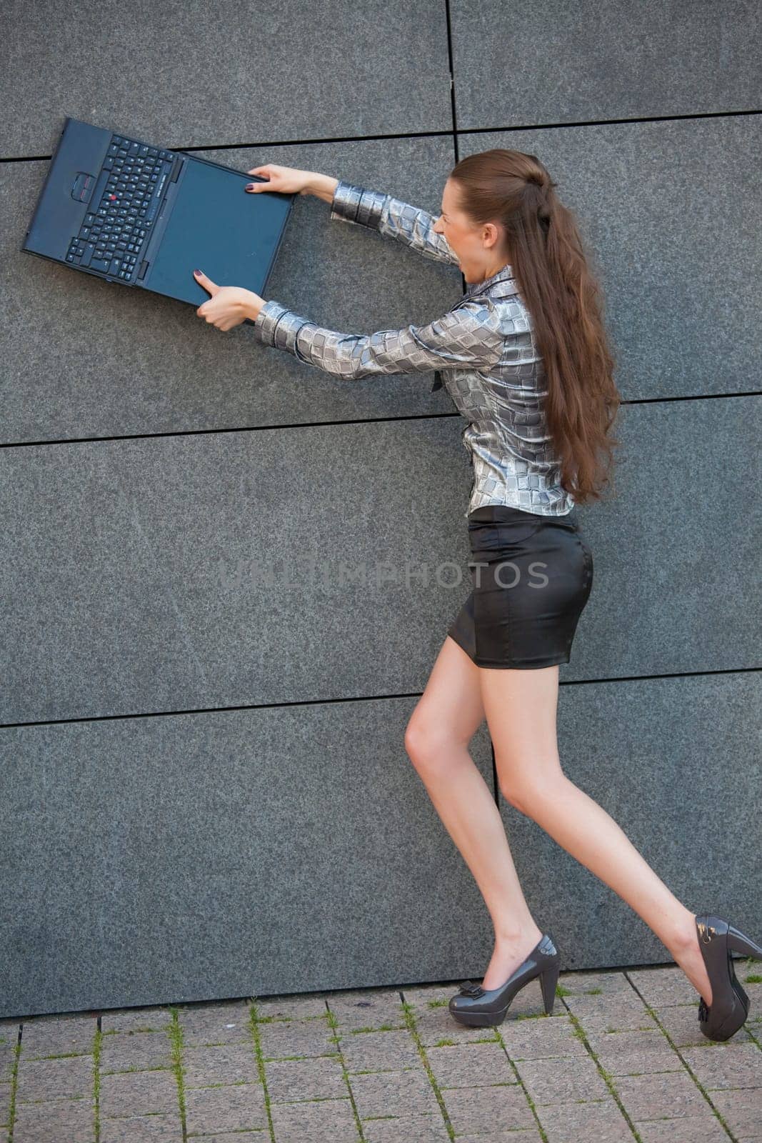 woman smashing laptop against wall