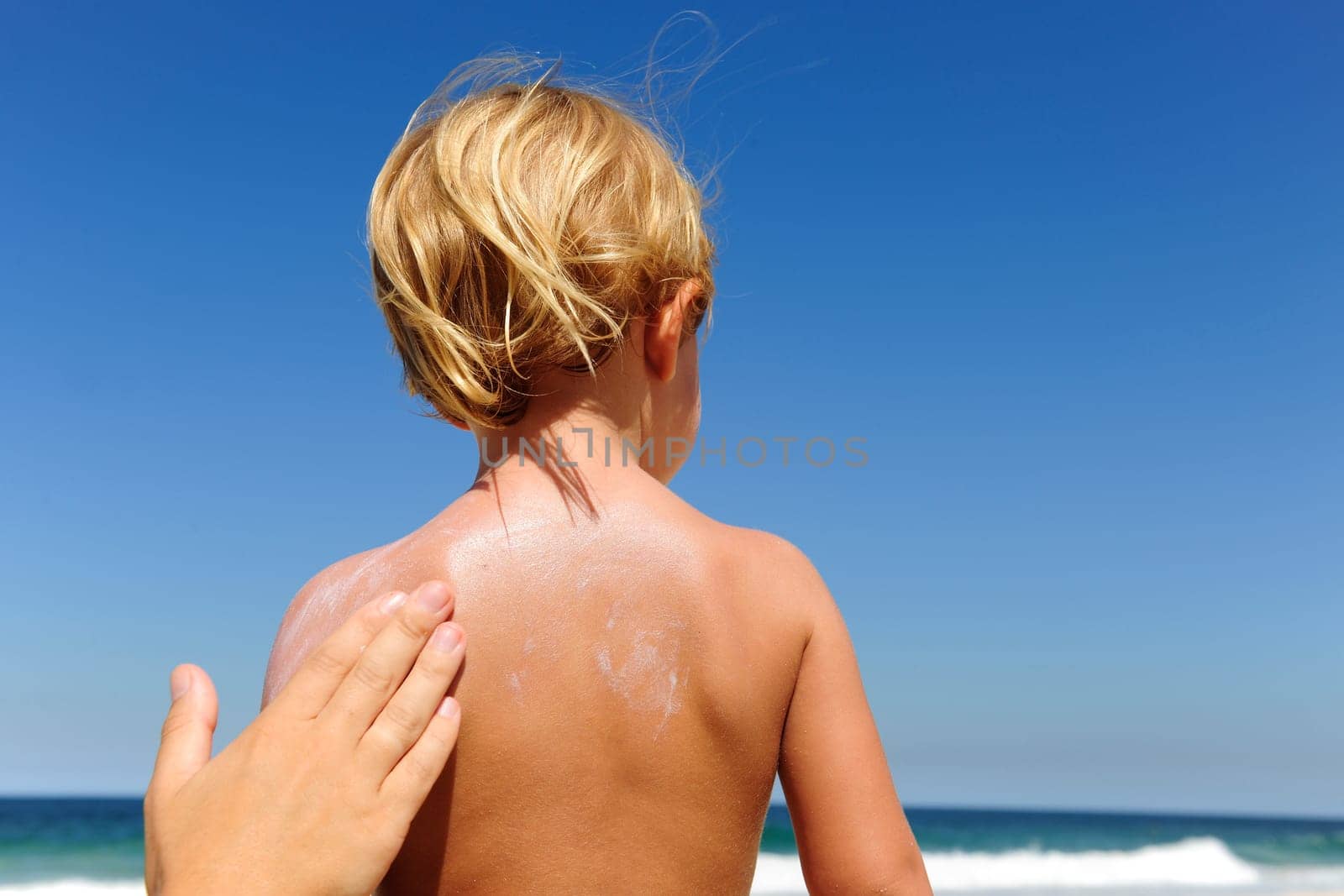 Mother applying sunscreen to child on the beach