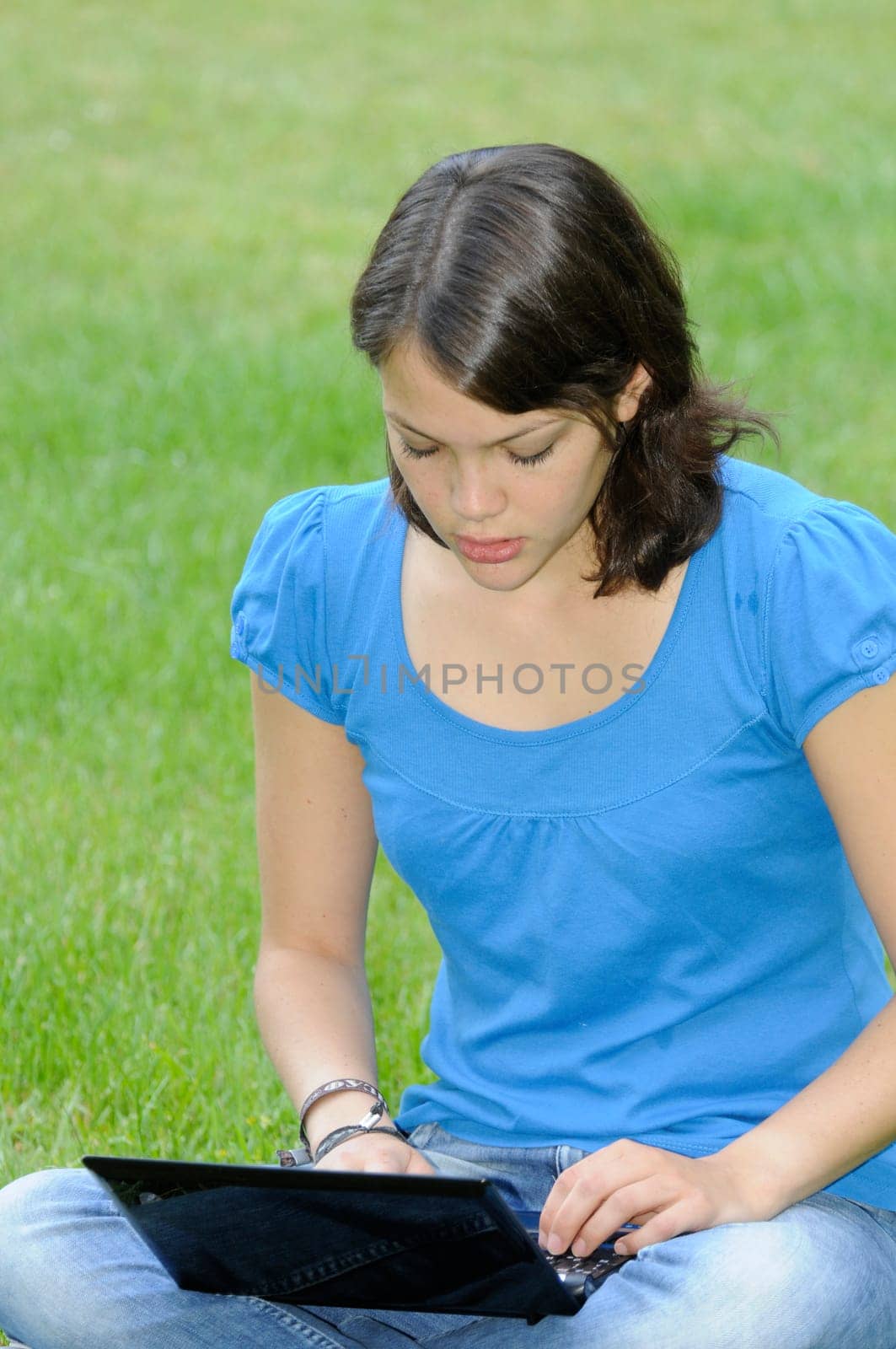 Teenage girl with netbook on meadow