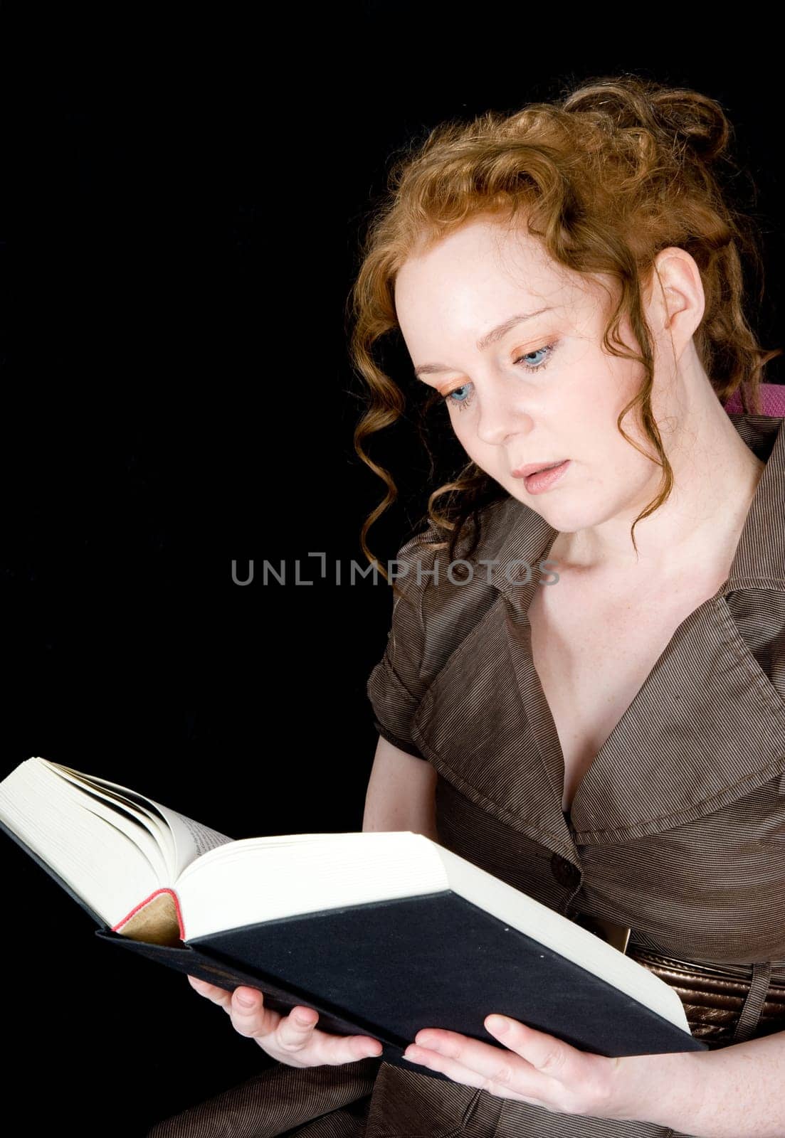 Beautiful girl with red hair reading a book