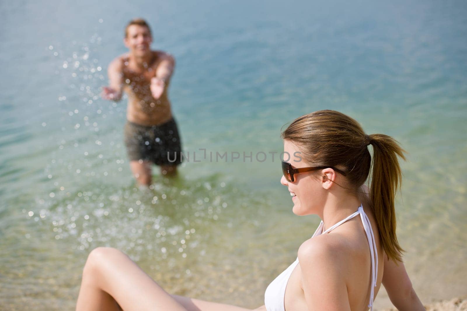 Couple on beach woman in bikini sunbathe