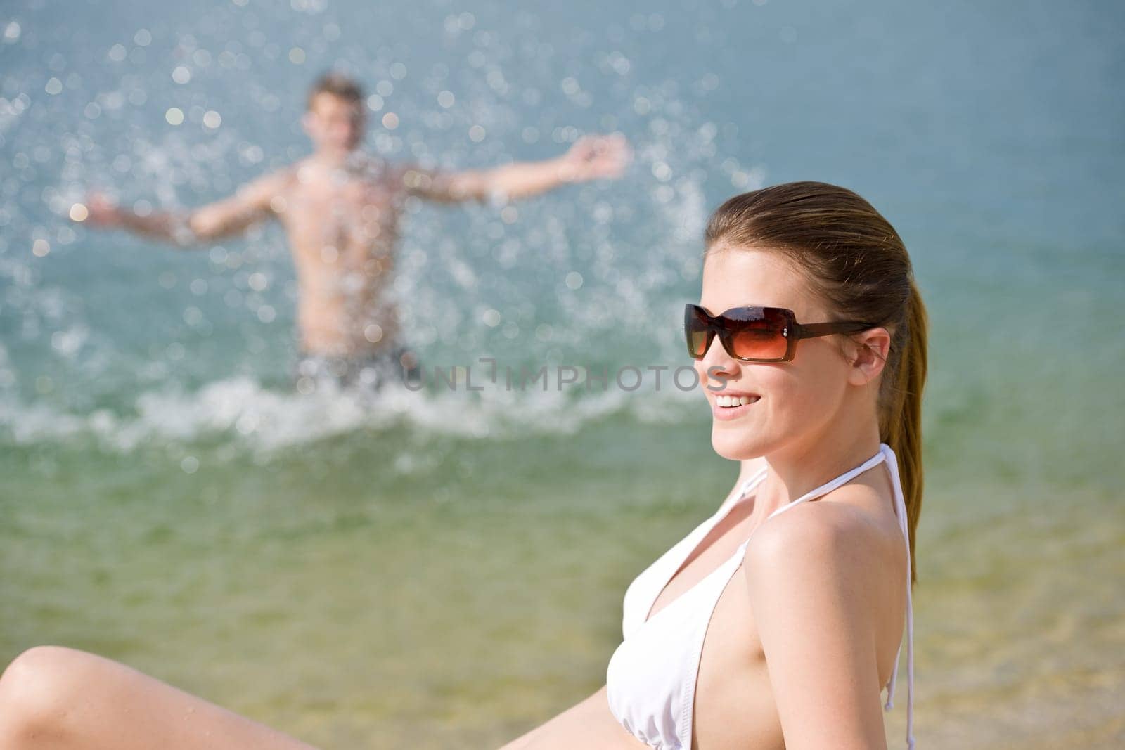 Couple on beach woman in bikini sunbathe
