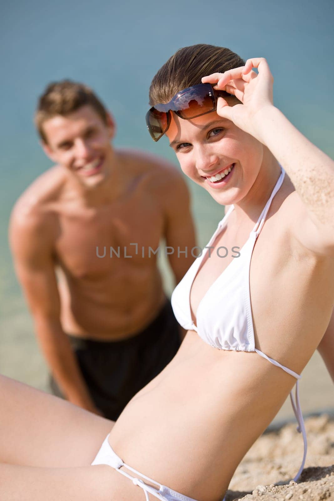 Young couple sunbathing by sea on beach