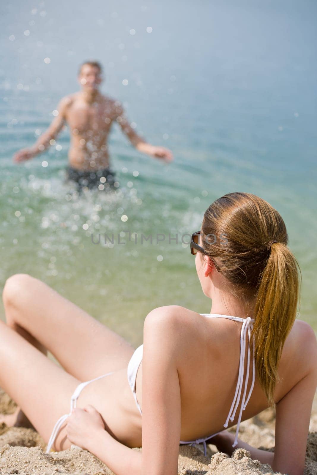 Young couple - woman sunbathing on beach