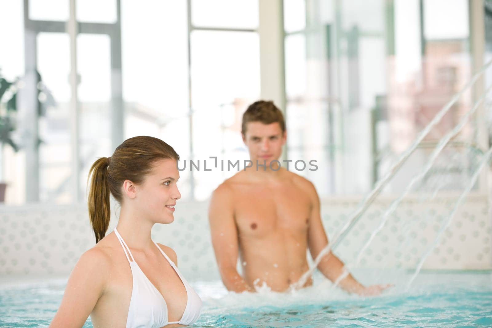 Swimming pool - young couple have fun under water stream