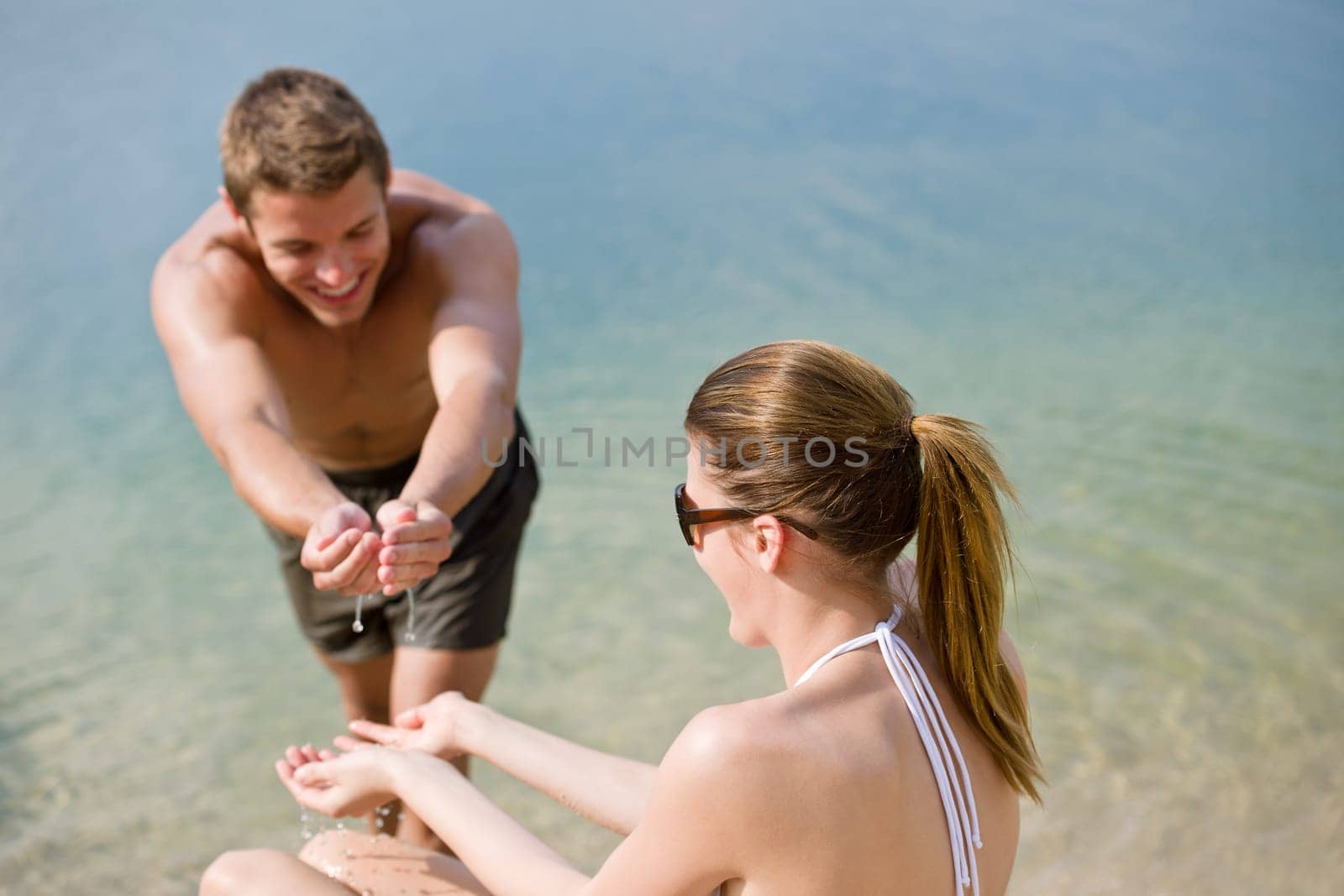 Couple on beach woman in bikini sunbathe