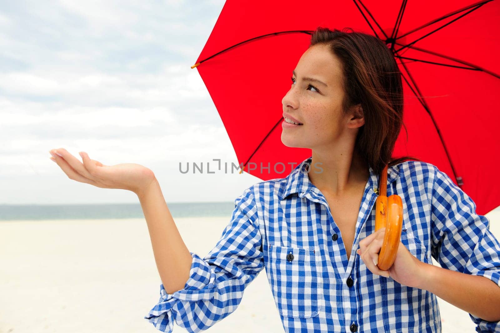 Rain woman with umbrella on the beach