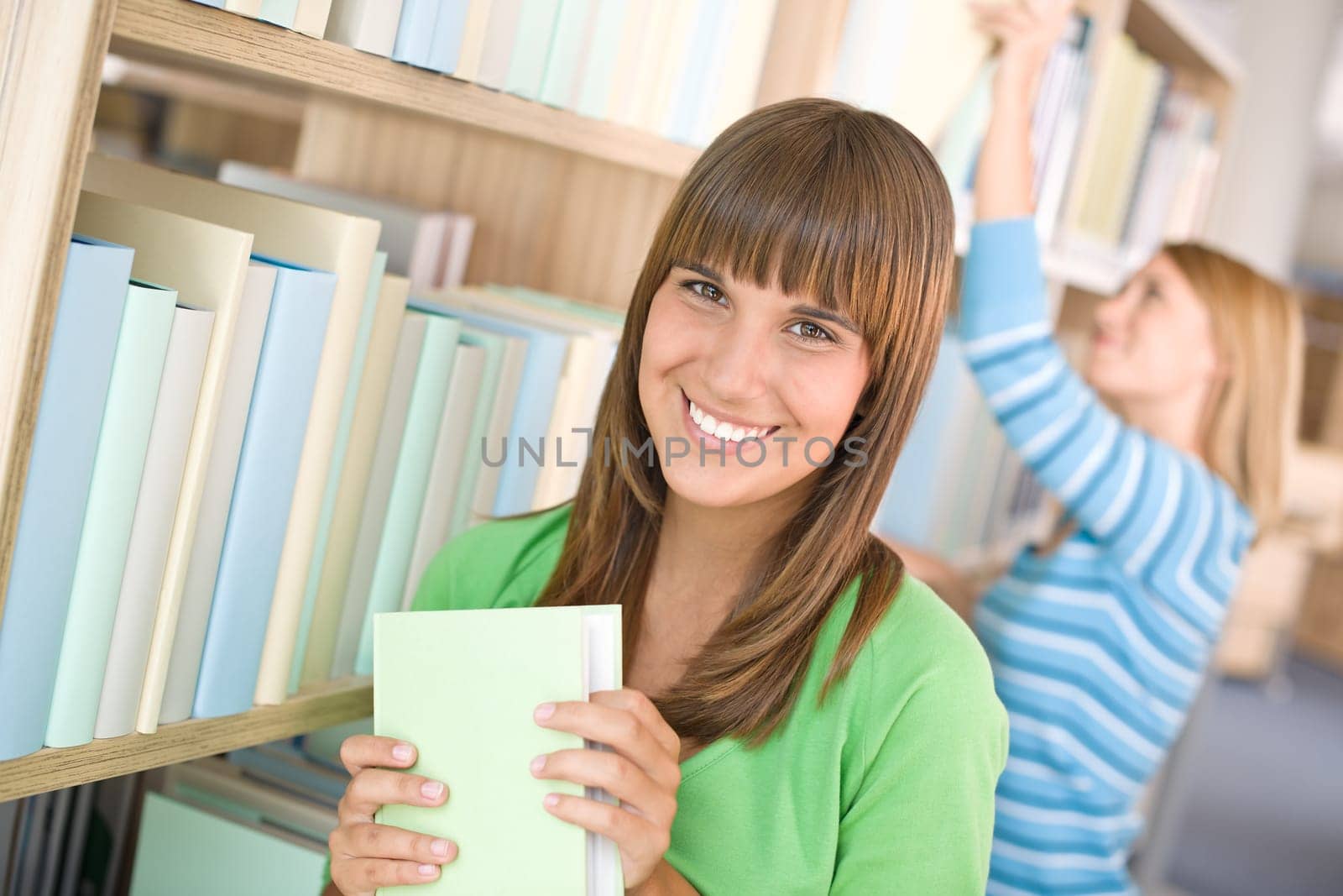 Student in library - two woman choose book