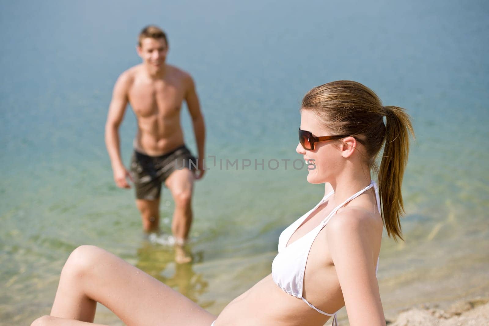 Couple enjoy summer sun on beach by sea