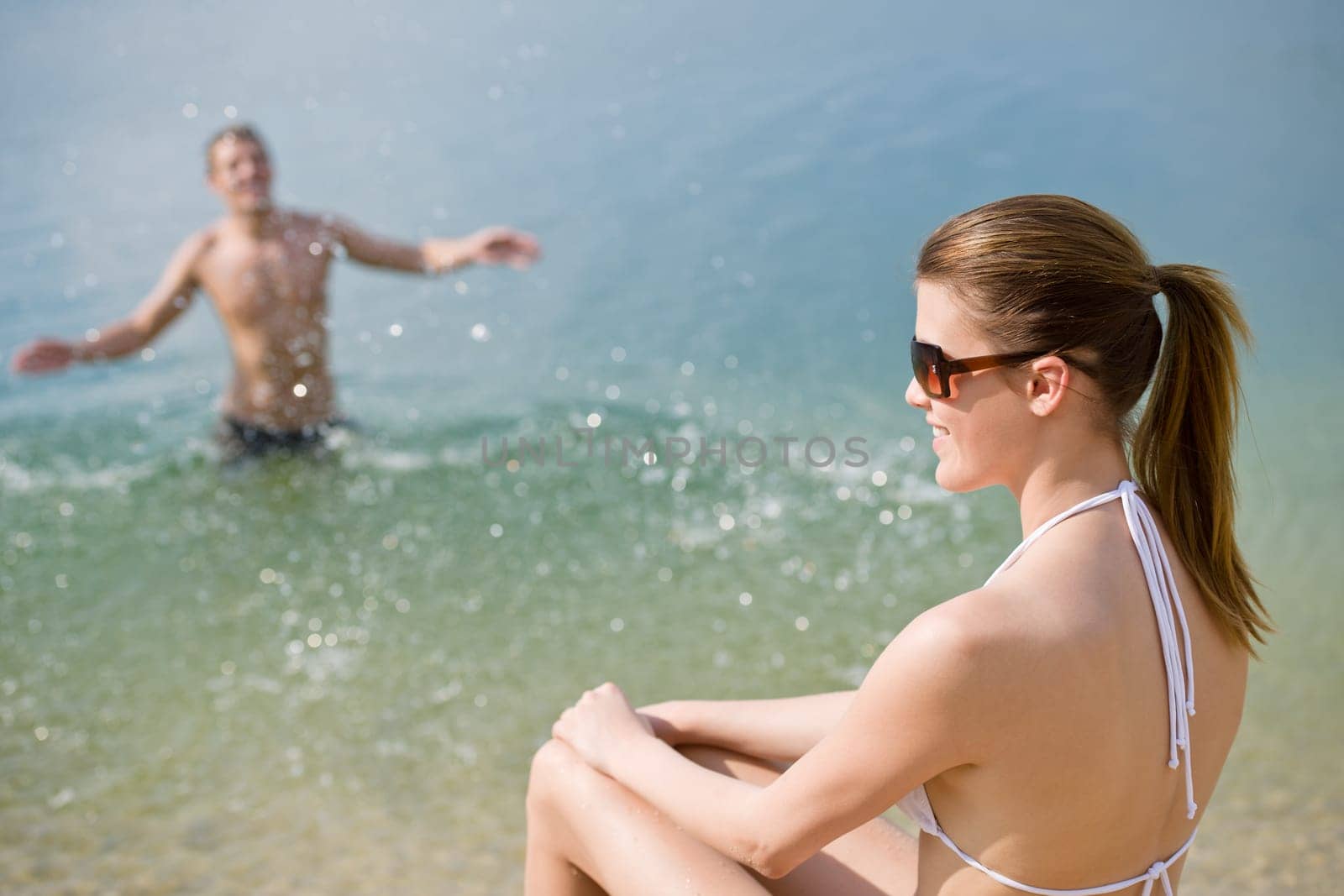 Young couple - woman sunbathing on beach