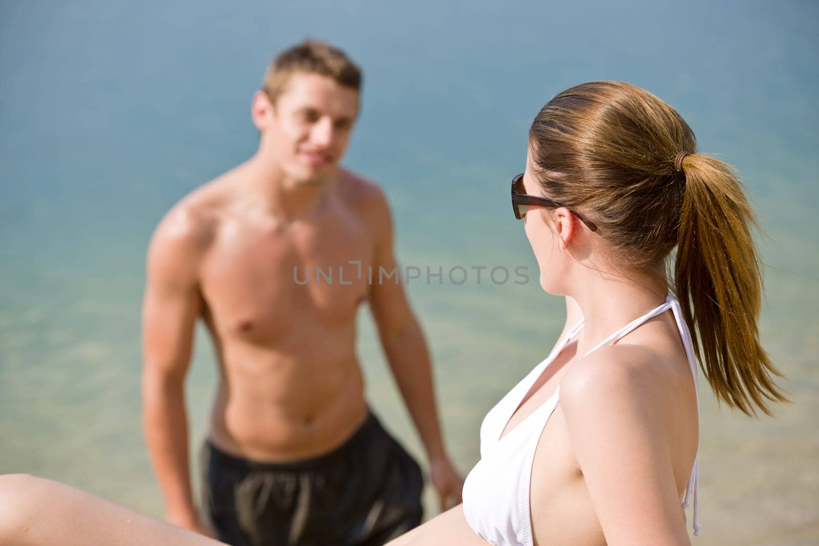 Young couple sunbathing by sea on beach
